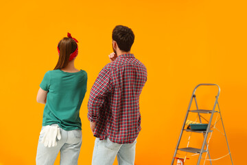 Wall Mural - Designers looking at freshly painted orange wall, back view