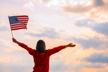 Hopeful Woman Holding The Flag Of The United Stated Of America. Optimistic Girl Holding American Flag Celebrating Citizenship
