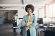 © Flamingo Images - Young businesswoman smiling in an office with colleagues in the background