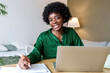 © Westend61 - Happy businesswoman with pen and laptop sitting at desk