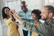 © Flamingo Images - Laughing team of diverse businesspeople standing with their hands raised together