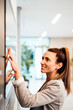 © Westend61 - Smiling businesswoman touching display screen at office