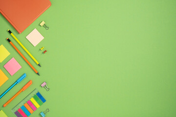 Frame of colorful school and office stationery set on green background. Flatly.