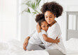 © JenkoAtaman - Happy ethnic family. African american mother and daughter tenderly embrace in bed