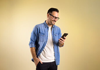 charming male entrepreneur with hand in pocket smiling and messaging over mobile phone. happy young 
