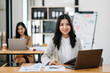 © Nuttapong punna - Young attractive Asian female office worker business suits smiling at camera in modern office .