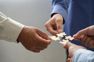 The concept of teamwork and partnership Hands joining puzzle pieces in office Businessmen put together a jigsaw puzzle - volunteer charity team business uniy.