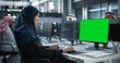 © Gorodenkoff - Arab Female Software Developer Working on Desktop Computer with Green Screen Mock Up Display. Young Middle Eastern Specialist Testing Programming Code for an Innovative Big Data Blockchain Project