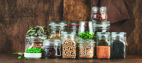 Wall Mural - Dried, raw and fresh legumes and beans in glass jars. Lentils, chickpeas, mung beans, soybeans. Healthy food, vegan protein, micronutrients and fiber sources. Rustic kitchen table