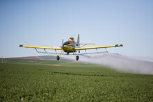 Close Up Image Of Crop Duster Airplane Spraying Grain Crops On A Field On A Farm