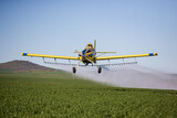 Fototapeta Łazienka - Close up image of crop duster airplane spraying grain crops on a field on a farm