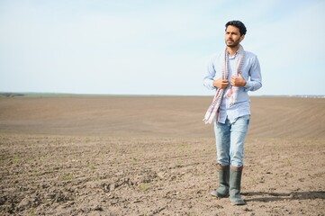 A young Indian farmer inspects his field before sowing.