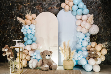 Arch with bears on background balloons. Photo-wall decoration space or place with beige, brown, blue balloons. Celebration baptism concept. Birthday party for boy. Trendy autumn decor with dry leaves.