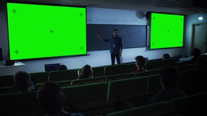 Leinwandbilder - Young Male Teacher Giving a Lecture, Showing Slides on a Green Screen Mock Up Display to a Diverse Multiethnic Group of Female and Male Students in Dark College Auditorium