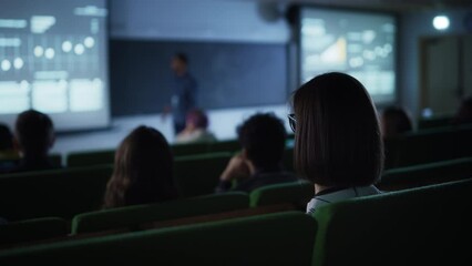 Aufkleber - Young Female with Short Hair Studying in University, Sitting in College Auditorium on a Lecture, Writing Down Notes in a Notebook. Over the Shoulder Footage from the Back on the Room