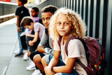 Fototapeta  - Excited blonde girl, 12, with bouncy curls chats with friends, anticipating the school bus arrival. Their laughter fills the morning air with joy. Generative AI