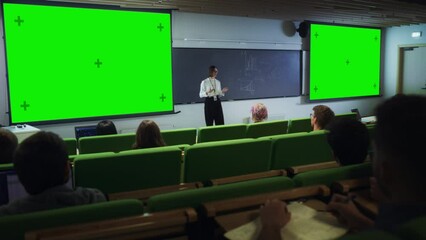 Fototapete - Young University Professor Giving a Lecture, Pointing on a Green Screen Mock Up Display. Group of Smart Diverse Students Study in Modern Classroom. Female Teacher Showing Content on Big Screens