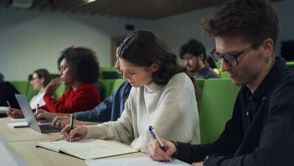 Fototapete - Talented Beautiful Female Student Studying in University with Diverse Multicultural Colleagues. She is Writing Down a Summary from the Lecture in Her Notebook