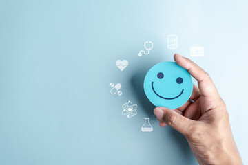 Hands holding blue happy smile face for medical care concept. mental health positive thinking.