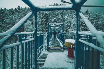 silhouette of man on the metal bridge in winter mountains