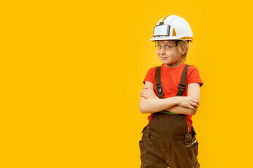 Wall Mural - Portrait of smiling boy in protective helmet, glasses and jumpsuit like worker. Yellow background. Copy space, mock up