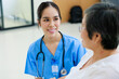 © NVB Stocker - Young asian doctor in blue uniform and senior woman holding hands together. Positive Asian woman caregiver helping patient.