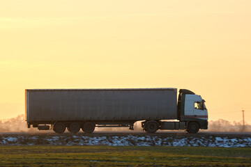 Wall Mural - Semi-truck with cargo trailer driving on highway hauling goods in evening. Delivery transportation and logistics concept