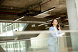 © BGStock72 - Young business woman using mobile phone in the office hallway