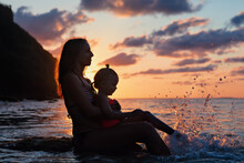 Happy People Have Fun On Summer Beach Holiday. Young Mother With Daughter Relax At Sea Water Pool. Looking At Beautiful View Of Sunset Sky. Healthy Family Lifestyle, Summer Travel On Tropical Island.