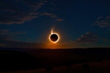 Total Solar Eclipse In Dark Sky Above Mountains, Mysterious Natural Phenomenon. Moon Passes Between Planet Earth And Sun. Beautiful Landscape With Solar Eclipse. Beauty Sunset