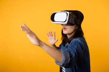 Poster - Young asian woman get experienced wearing virtual reality headset game entertainment isolated on yellow background. Winner of cyber future video game concept.