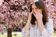 Girl Standing Outside Rubbing Eyes Because of Allergy to Pollen During Spring Blooming. Crying Because of the Allergy. Allergy Symptoms and Health Condition Concept