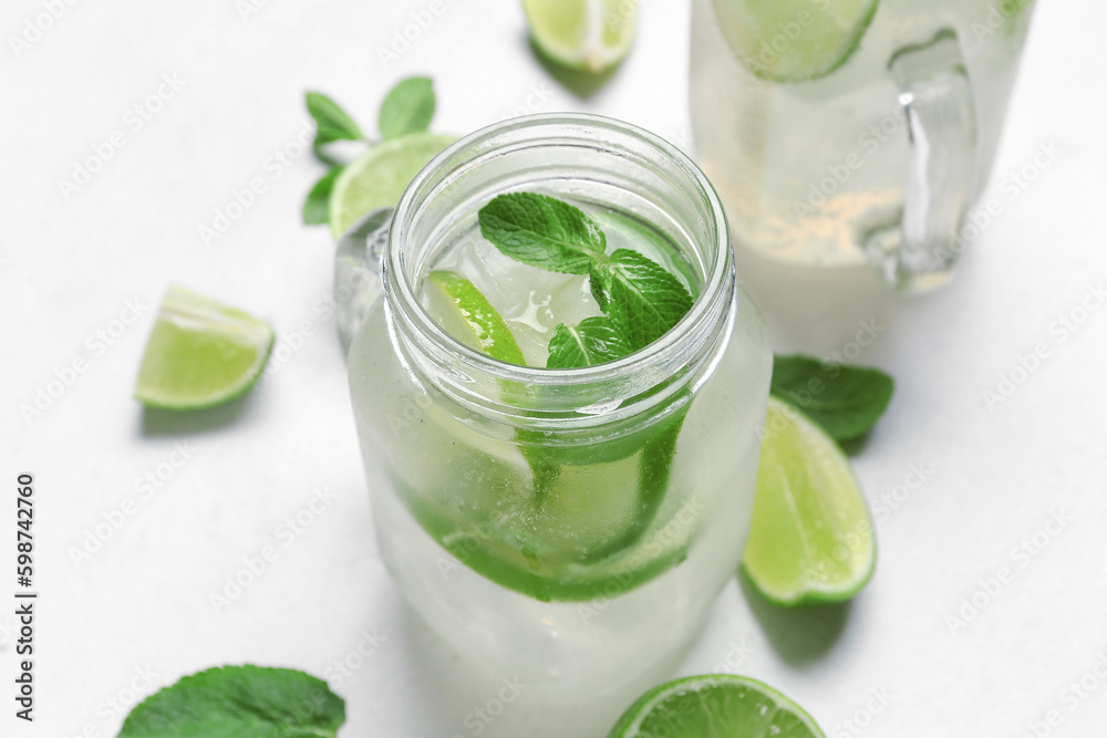 Mason jars of tasty mojito on light background