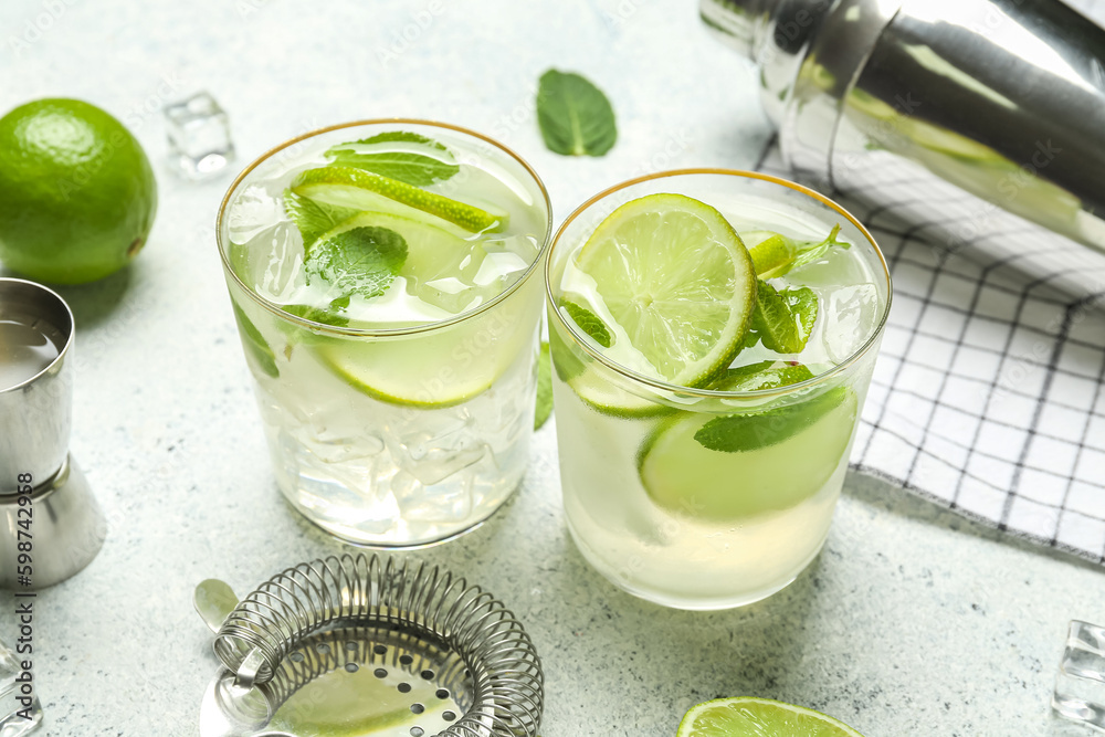Glasses of tasty mojito on light background