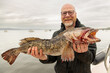 Happy ling cod fisherman holding a dead and bloody fish after his catch in the Puget Sound of Washington State