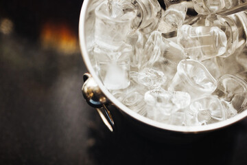 Wall Mural - Ice cubes background. Metal bucket. Alcohol serving bar. Whisky on rocks drinking. Black bar counter. Exclusive cocktail bar background.