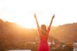 Happy woman with arms raised  making the victory sign with her fingers and sunset in the background. Concept of person overcoming problems and achieving success.