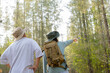© maya1313 - Young Asian man and woman with a backpack and hat hiking in the mountains during the summer season, a traveler walking in the forest. Travel, adventure, and journey concept.
