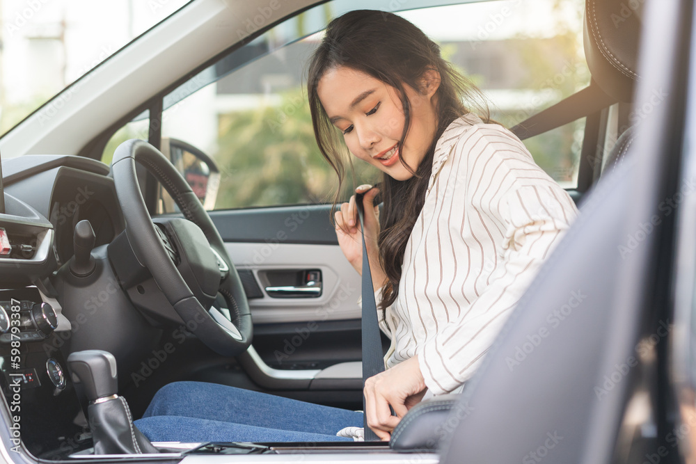 Happy smile brunette asian young woman hand fastens a seat belt sitting in front of car before driving, vehicle for travel, trip take a safe journey, attractive driver with safety belt, transportation