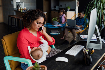 young latin mother working at home using computer while she breastfeeds her baby son in Mexico Latin America, home office concept, hispanic family