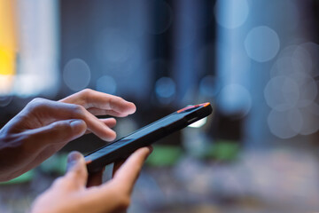 Close-up male hand using smartphone at meeting room blur bokeh background. searching data networks or chatting online. typing sending message. mockup mobile phone wireless.