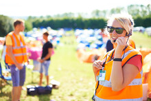 Festival Security, Communication And A Woman Outdoor On A Grass Field For Safety At A Music Concert. Party, Event And Crowd Control With A Female Officer Using A Headset Microphone For Generative AI