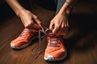 Unrecognizable young runner tying her shoelaces. Studio shot on wooden floor background.