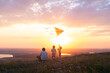 © Юля Шевцова - Happy man and children, father and sons, with kite in nature at sunset