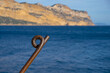 Rusty twisted metal armature. Mediterranean coast background. An old way of mooring a boat. Copy space.