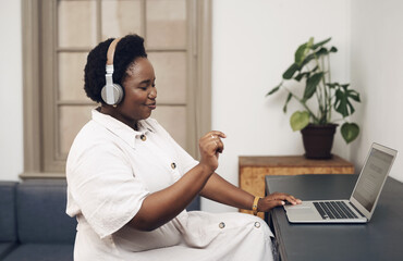 Poster - Good music is the ultimate work motivator. a young businesswoman using headphones and a laptop in a modern office.