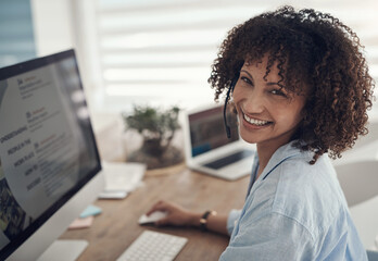 Who needs an office to get work done. an attractive young sitting alone at home and using her computer while wearing headsets.