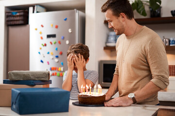 Wall Mural - Go ahead and open your eyes now. a man surprising his son with cake and gifts on his birthday.