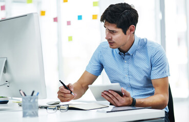 Aufkleber - Hard work is what gets him further. a young businessman writing notes while using a digital tablet and computer in an office.