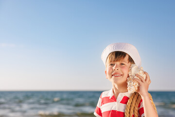 Poster - Happy child listen seashell on the beach